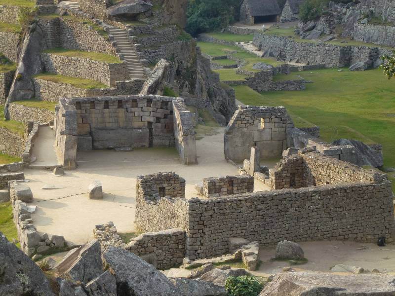 a close up of some ruins of buildings that were built by stone, there are also some steps and terraces covered in grass and many walls