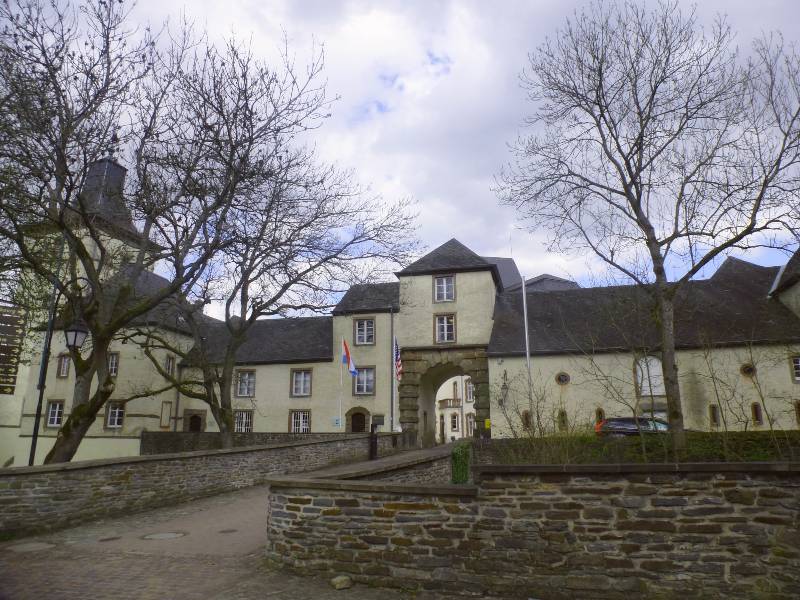The entrance to Wiltz Castle, the castle is painted an off white and has various levels and an arch way goes through the entrance. It's one of many castles in Luxembourg