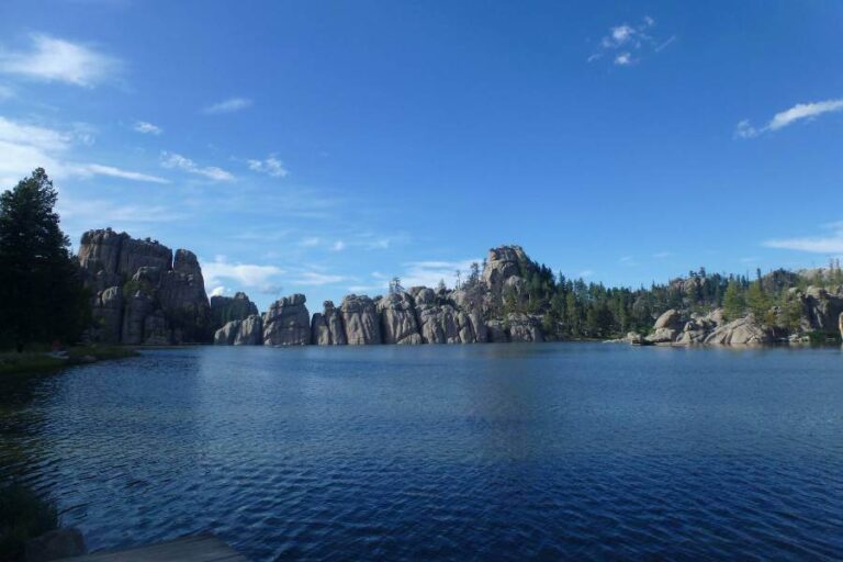 a blue lake, surrounded by rocks and trees at the shoreline