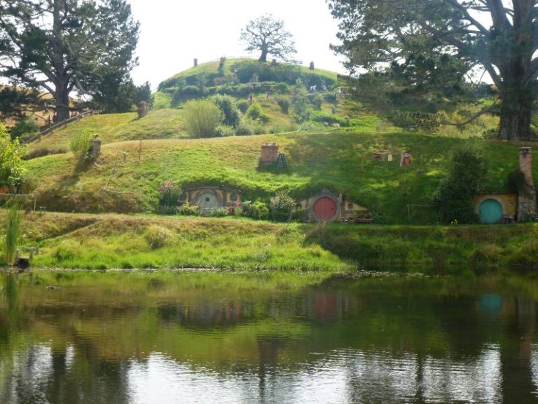 lots of hobbit houses across the lake, a few big trees and very green grass