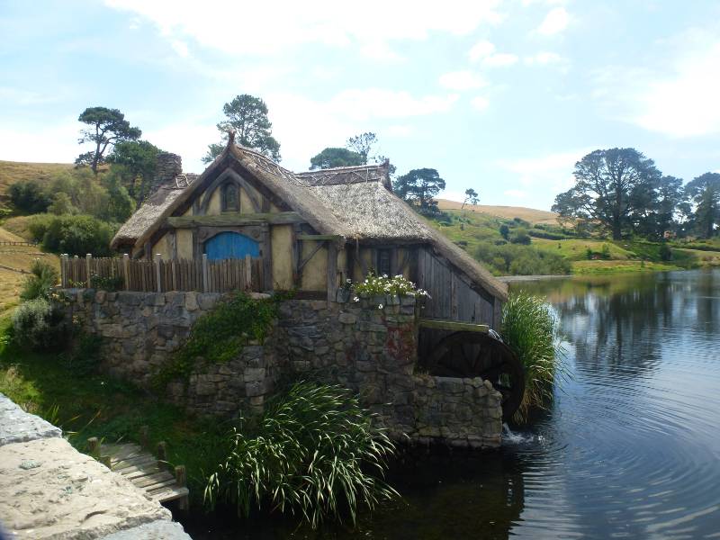 water mill at hobbiton at the side of the lake in an old tudor style