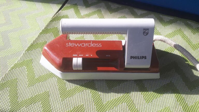 a red and white travel iron on a green and grey mat