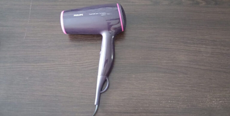 a purple hair dryer laid on a wooden table