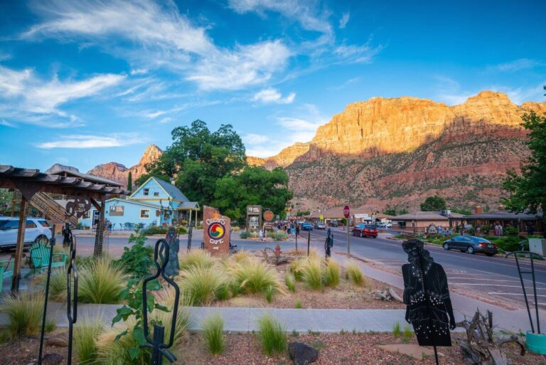 a road through the town of Springdale with buildings and the orange cliffs of Zion Canyon in the distance