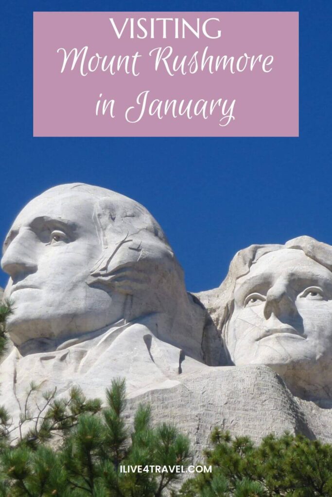 Pinterest pin featuring a close-up view of Mount Rushmore National Memorial, highlighting the detailed stone carvings of George Washington and Thomas Jefferson set against a brilliant blue sky. Green pine trees frame the base of the monument. A text overlay at the top reads, “Visiting Mount Rushmore in January”