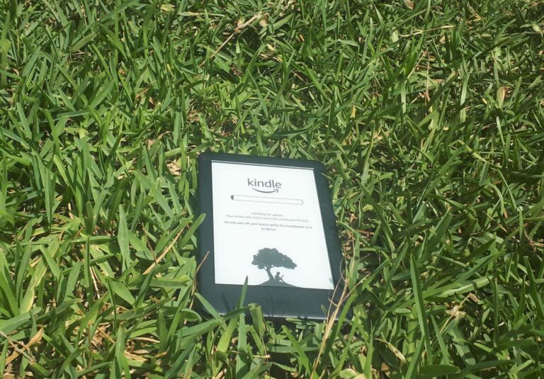 a kindle that is open and updating and is laid on some green grass