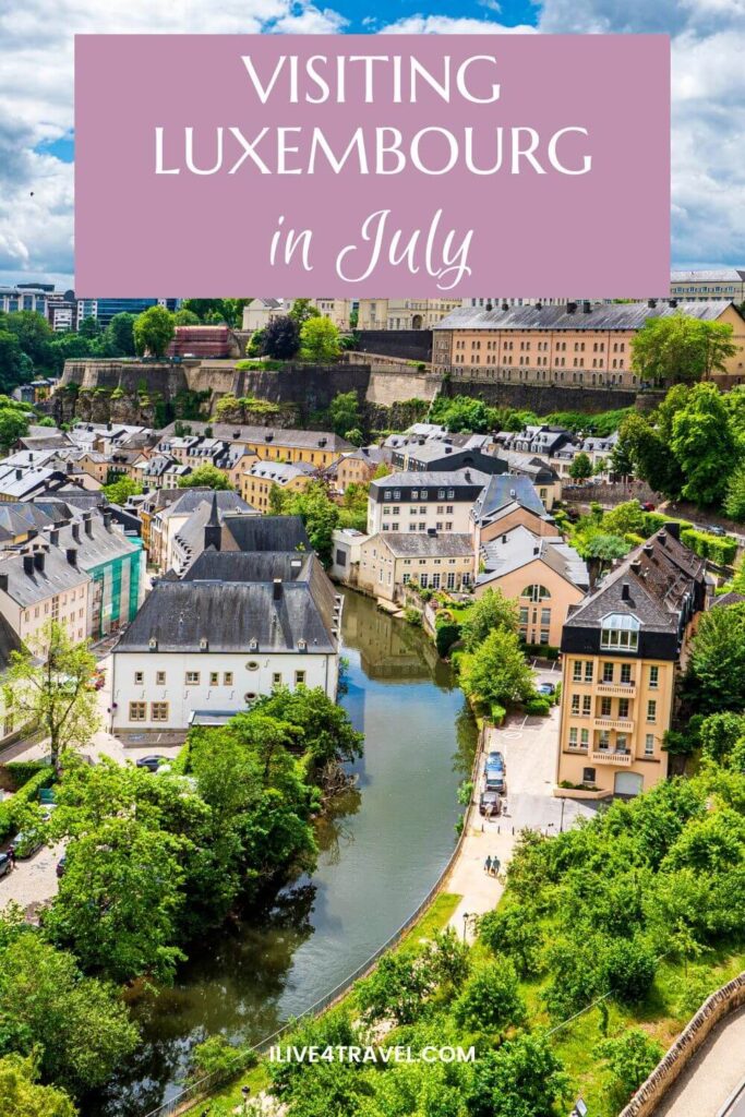 a pinterest pin about visiting luxembourg in july, showing a valley with a river running through it and houses in the valley and on the cliff above the valley