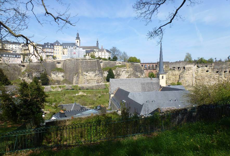 a view looking from one side of the valley to the other, with a stone valley and on the top of the cliff overlooking the valley are lots of buildings mainly white or yellow