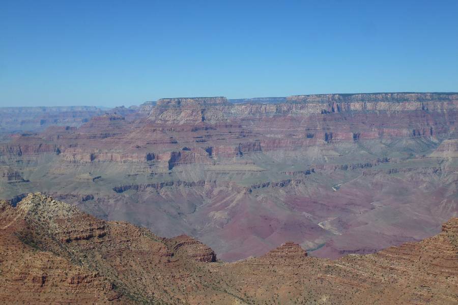 a deep canyon, showing the different colors of the sides of the canyon from red, green, white and orange on a beautiful sunny day with no clouds in the sky