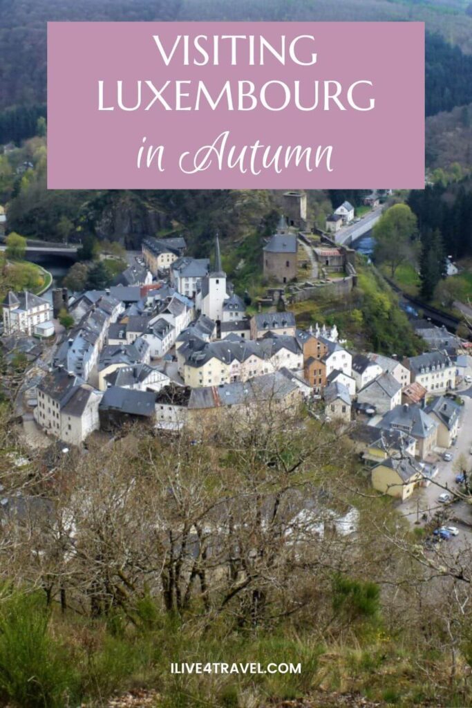 a pinterest pin about visiting luxembourg in autumn showing an image from above of some castle ruins with a town of white houses surrounding it