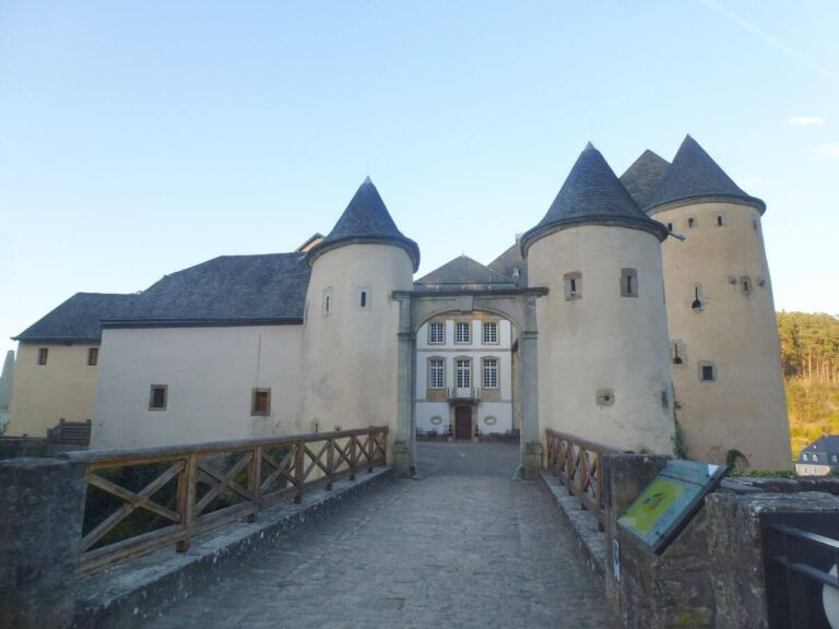 the walkway to a beige castle with round turrets