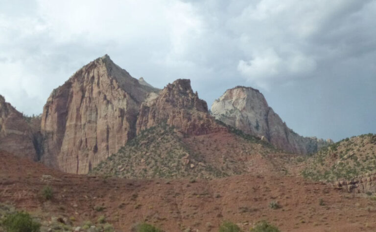 orange and white canyon wall sides with a few bushes on the slopes