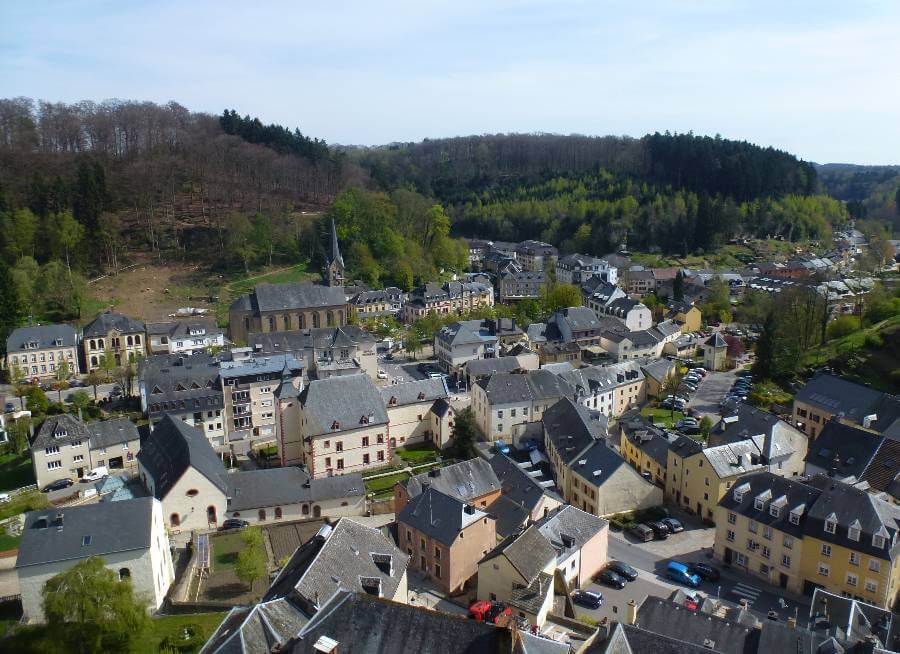 buildings in a city, surrounded by hills and trees with a church viewed from above