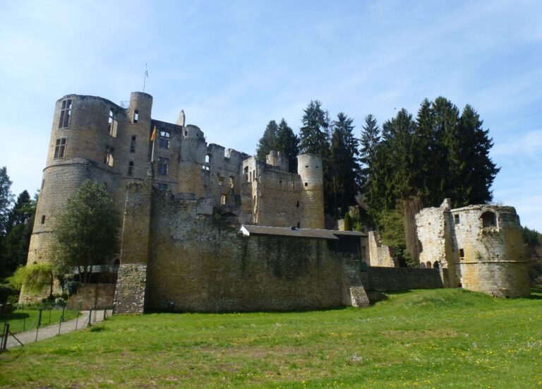 the ruins of a castle on a sunny day with grass in front of it