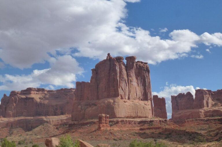 a huge orange rock that has been eroded around over millions of years to leave the surrounding area flat