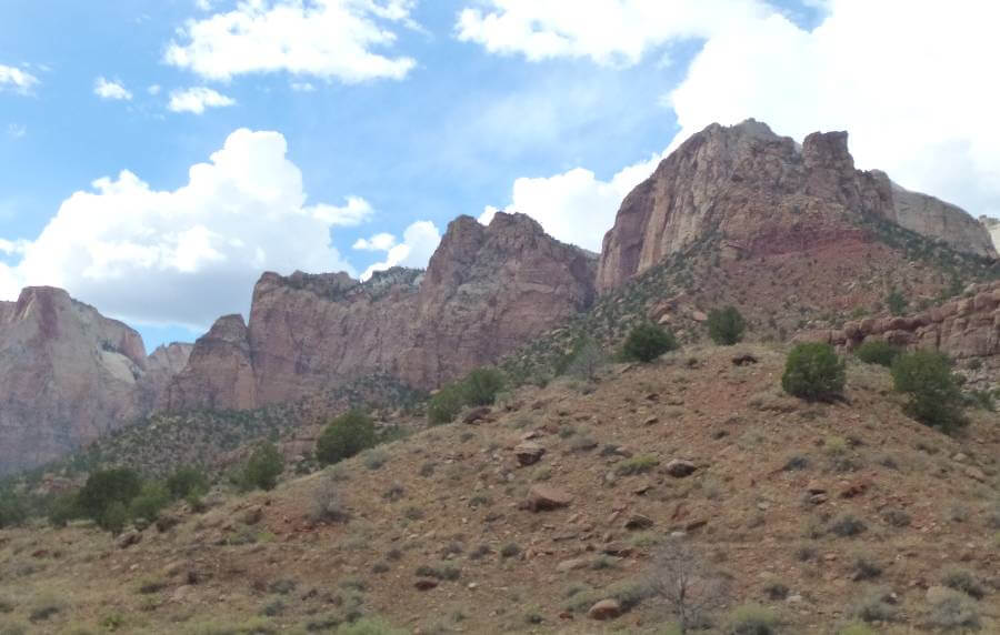 orange slopes and cliffs of a canyon with rocks and bushes on the slopes