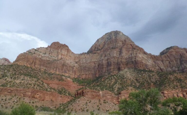 the sides of an orange canyon with trees at the bottom