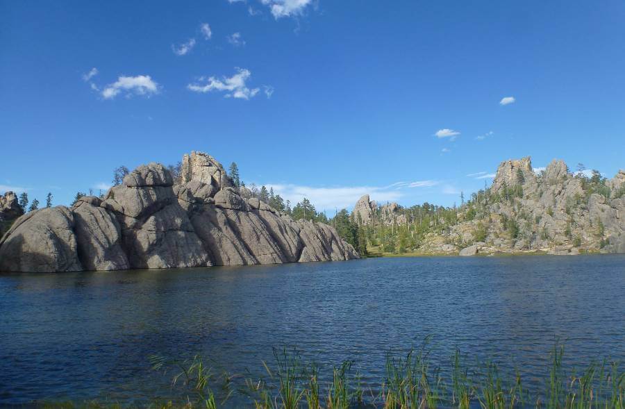 a large lake with huge boulders around the side of it, with a few trees on the slopes