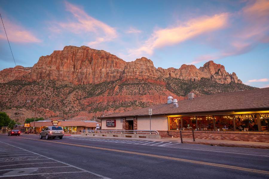orange cliffs in the background with a restaurant and a motel next to a road 